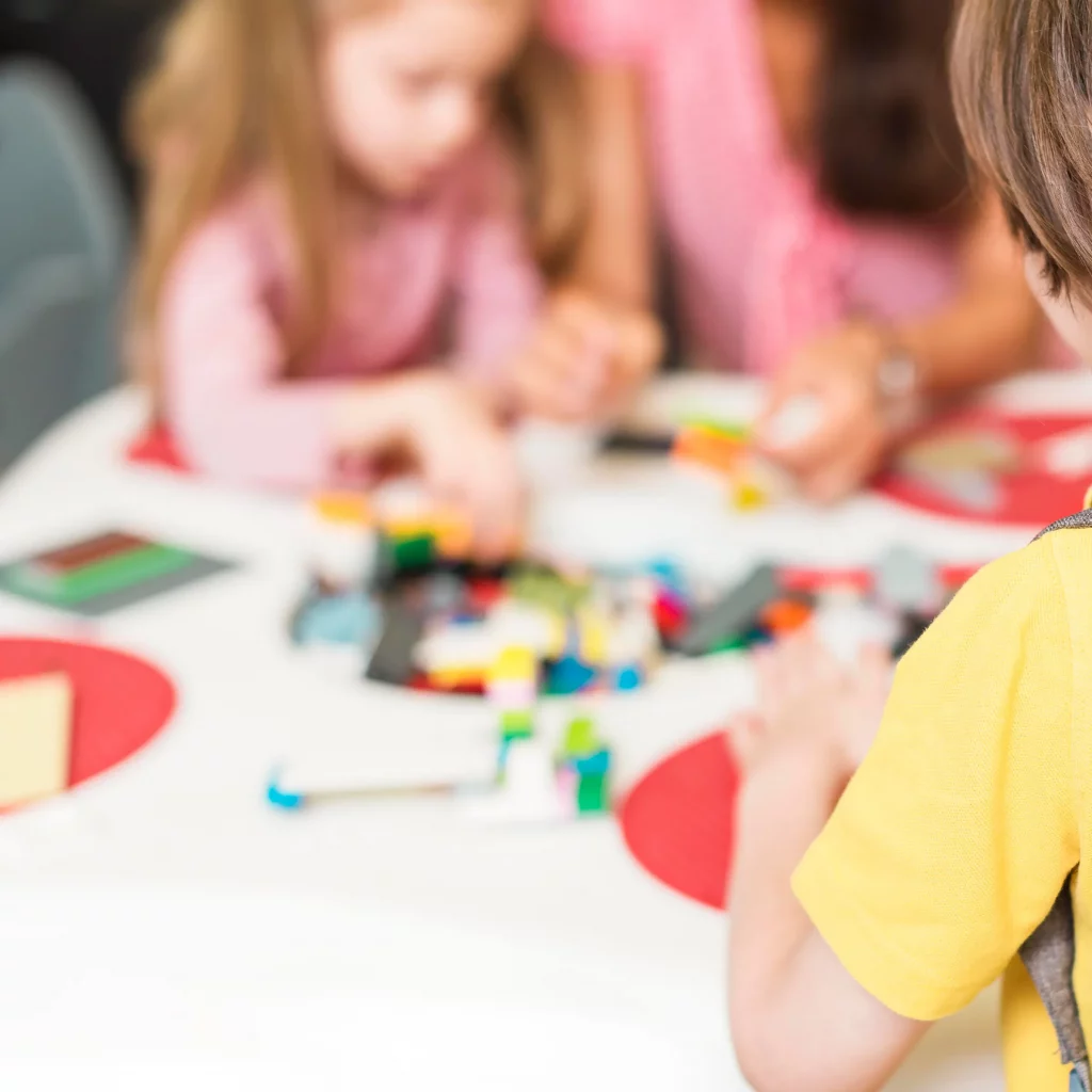 STEAM Education – Praxisbeispiel: lernende Kinder um Tisch, diffuse Ansicht